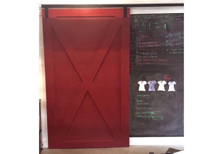 Bright red sliding barn door with black hardware next to chalkboard 